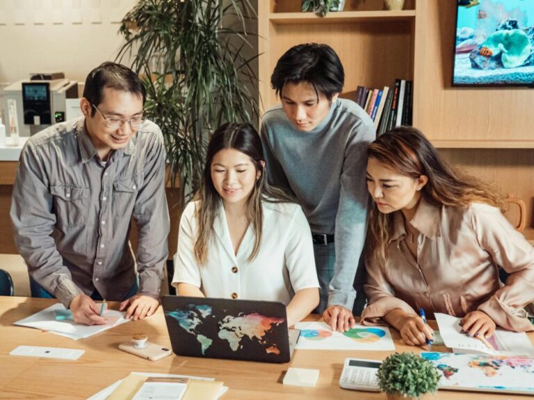 Un groupe diversifié de professionnels collaborant sur un ordinateur portable dans un environnement de bureau moderne.
