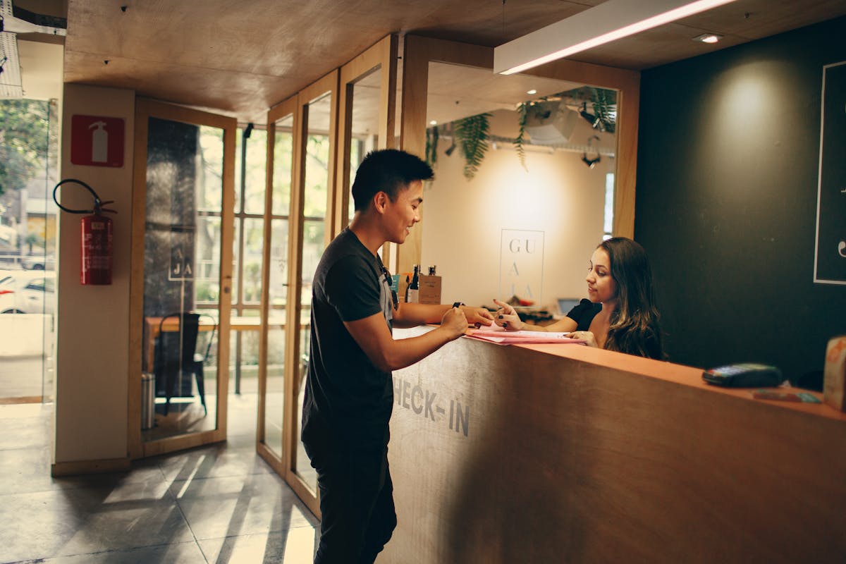 Traveler checking in at hotel reception desk using English phrases