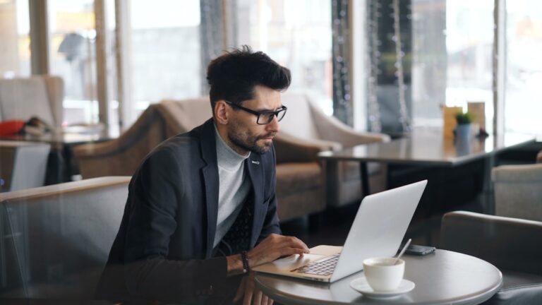 a man sitting at a table using a laptop computer