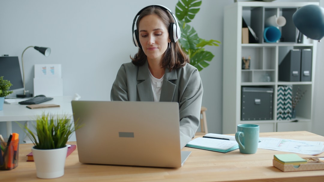 Happy businesswoman is typing in office using laptop then dancing raising arms wearing headphones. Modern technology, work br