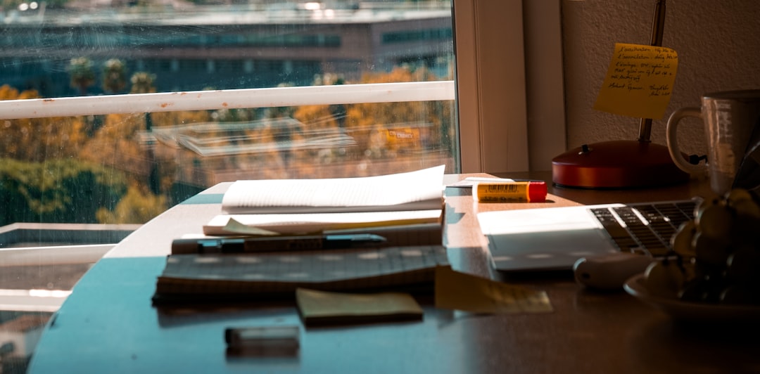 A desk with papers, a view, and a lamp.