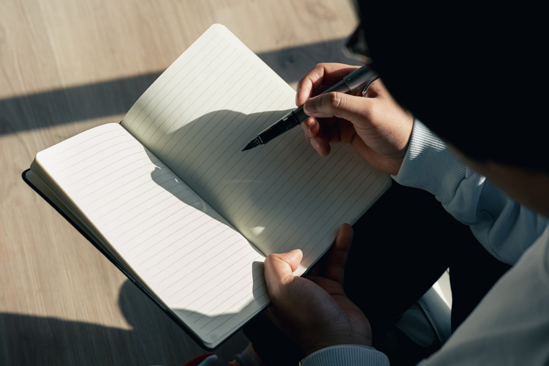 A person sitting down writing on a notebook