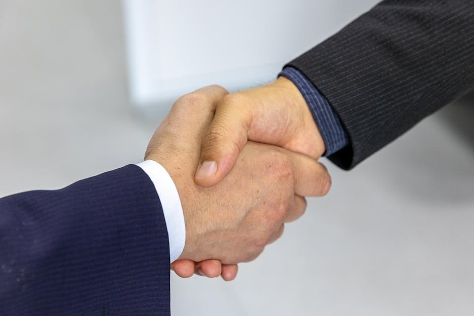Close-up of two businessmen shaking hands, symbolizing agreement and partnership. — body parts English idiom