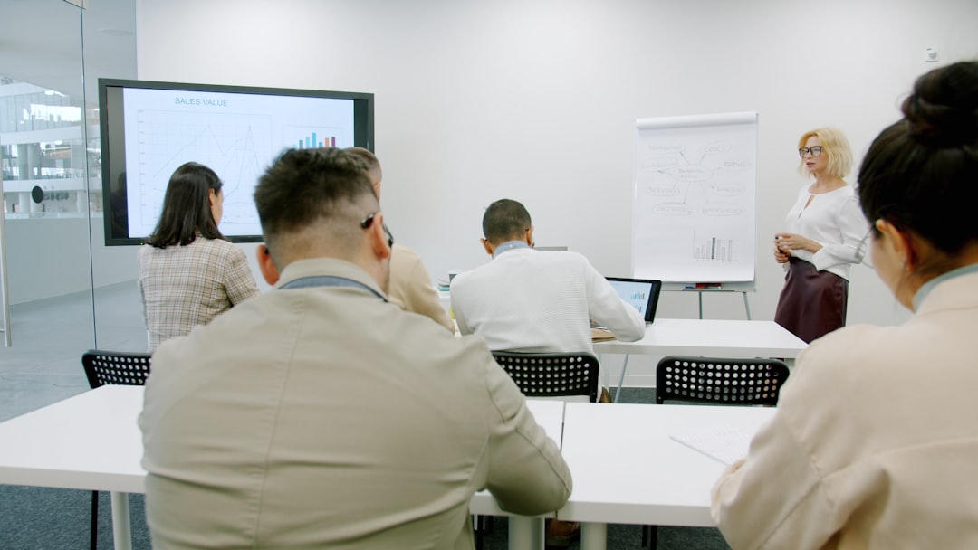 Mature businesswoman making presentation in office room for employees talking pointing at information of board. People and mo