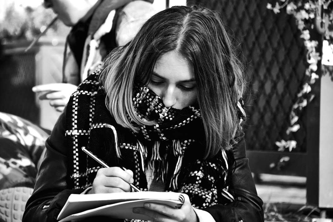 Young woman writing in a notebook with a pen.