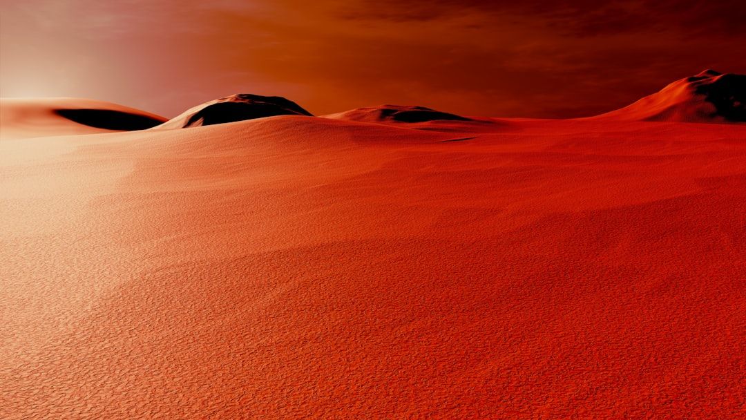 a group of hills covered in sand under a cloudy sky