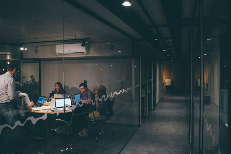 多益單字 office vocabulary — workers meeting in a glass conference room
