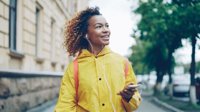 Daily English listening practice — a woman using earbuds and her phone while walking