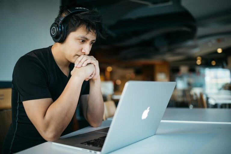 英文聽力 practice — a man wearing headphones focused on a laptop