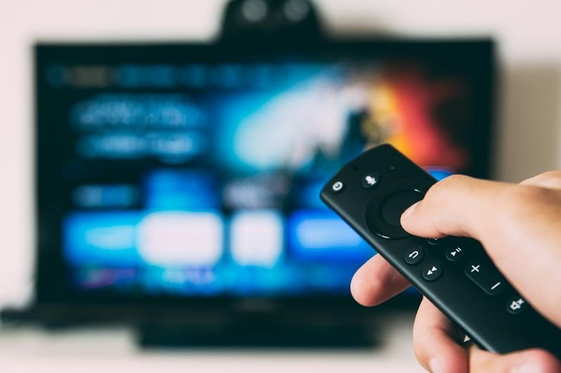 Learning English with Netflix shows — a hand holding a remote in front of a streaming TV