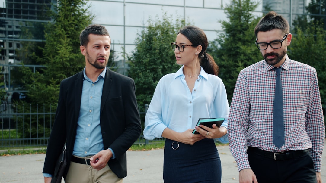 Cheerful colleagues men and woman are walking outdoors near office center talking smiling enjoying work break and cooperation