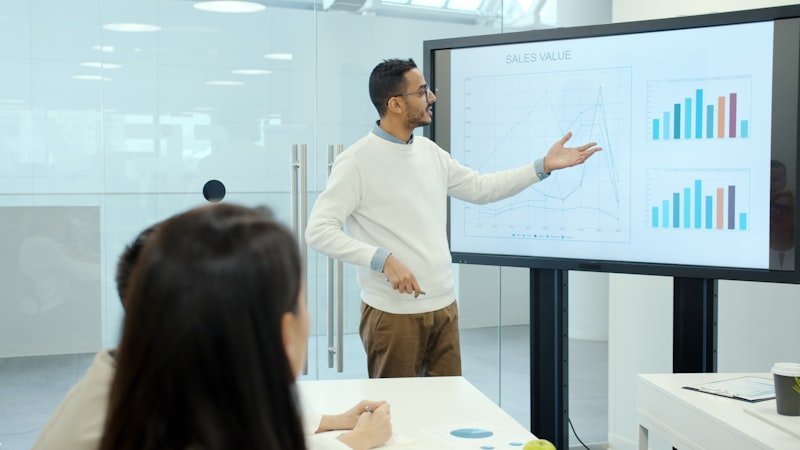 man presenting business charts 英文簡報 on large screen