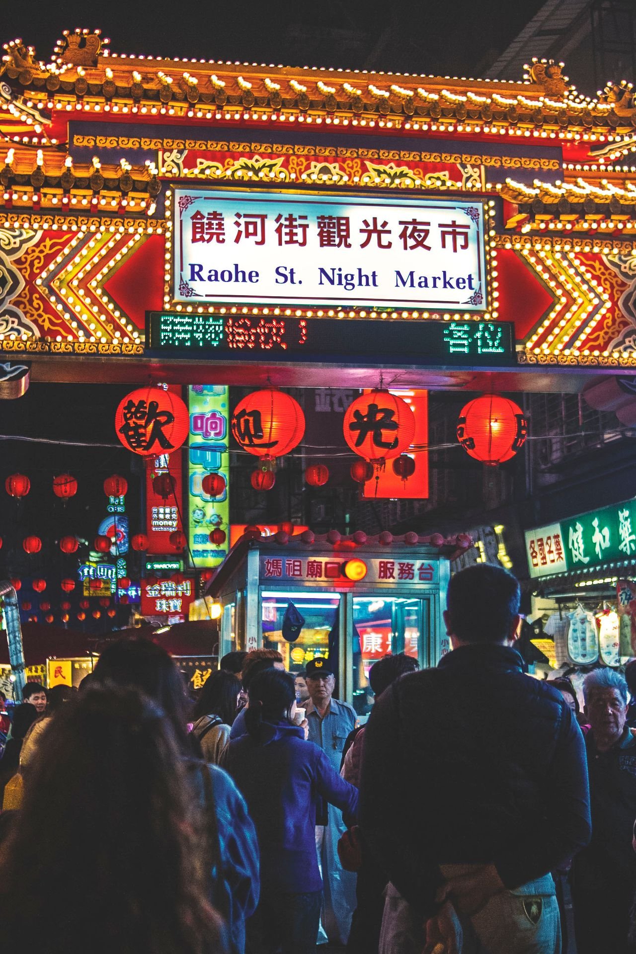 Illuminated Raohe Street Night Market entrance in Taipei with neon signs and red lanterns