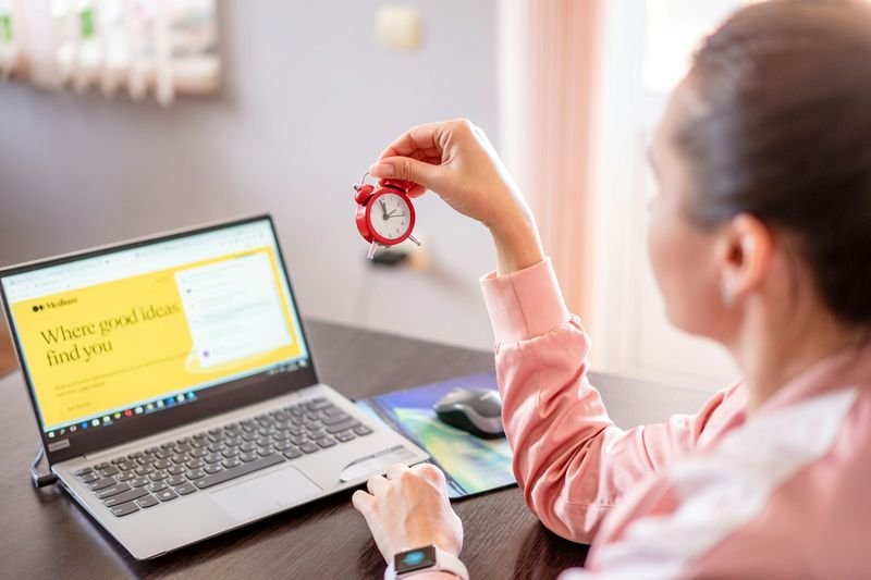 Office deadlines EOD and ASAP — woman holding clock at desk