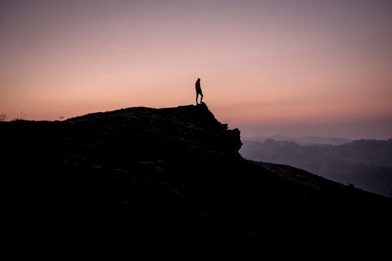 登山者站在山頂迎接日出，象徵勵志英文諺語的堅持精神