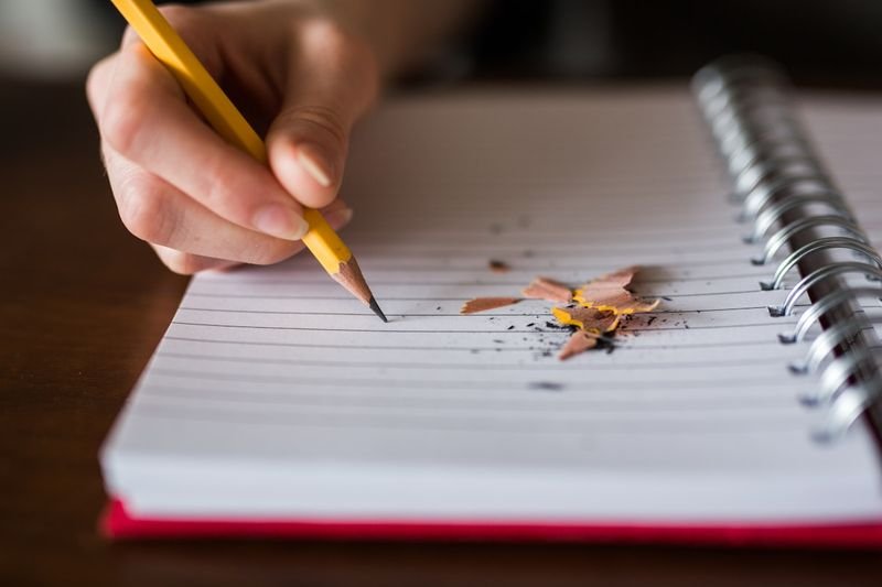Student writing English phrasal verbs in a notebook to study daily English