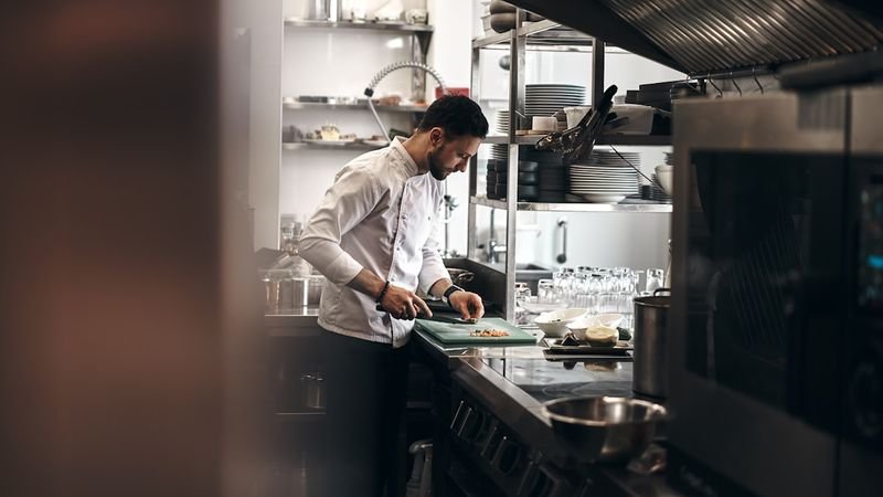 餐廳英文 chef plating a fine dining dish in a professional kitchen