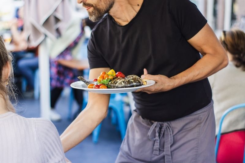 餐廳英文 server delivering a plated meal to diners at a table