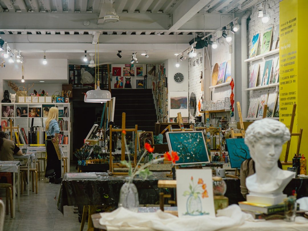 An art studio in Taichung, Taiwan, features easels with canvases, art supplies, and sculptures, while students engage in crea