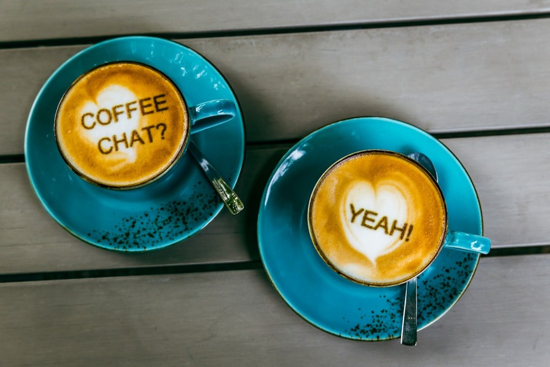Communication by coffee.Two cups of freshly brewed coffee (cappuccino) on a table, with the following text on the coffee fo