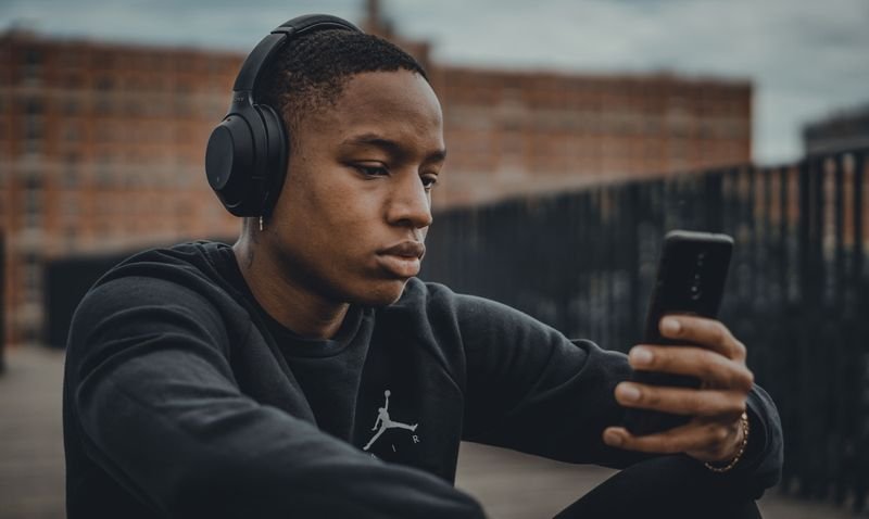 Learner listening to a podcast on a phone to train the ear for connected speech
