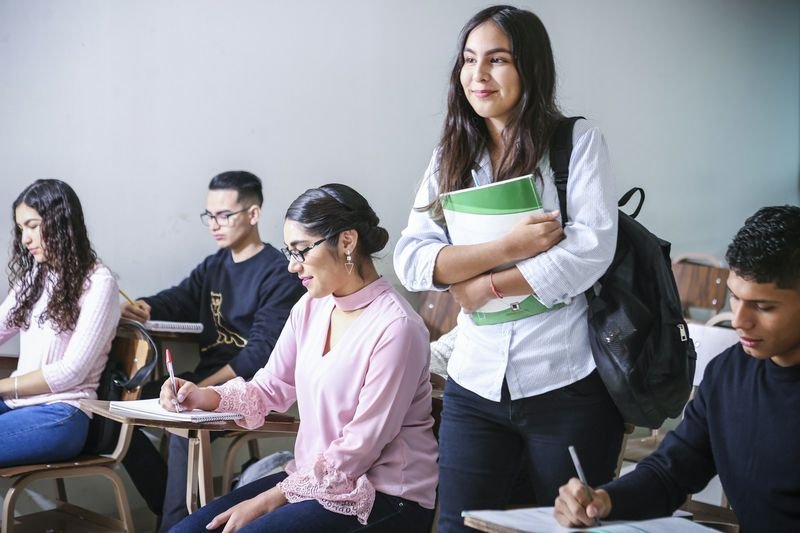 Students studying English with textbooks alongside a foreign teacher in class