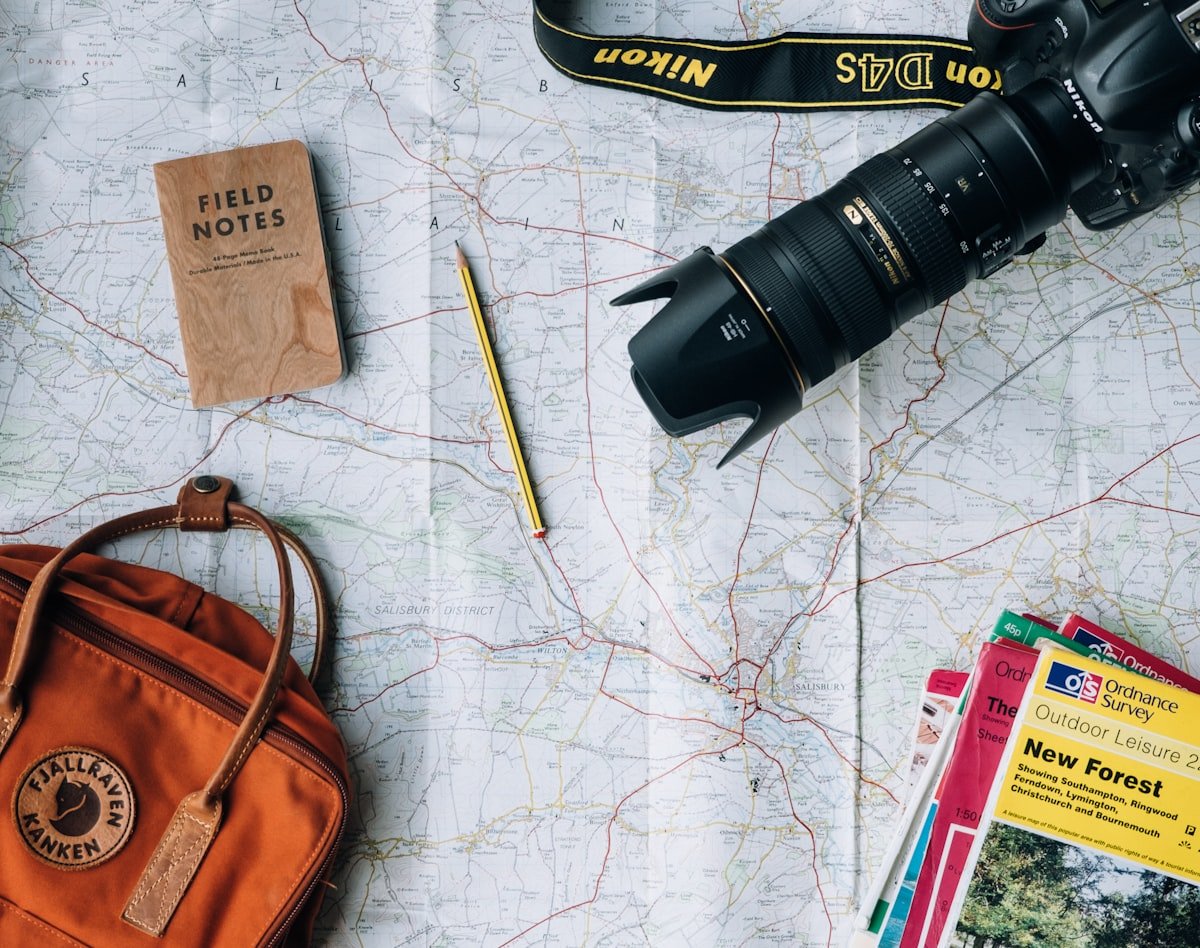 Flat-lay of a travel map, backpack, camera and guidebook laid out for trip planning