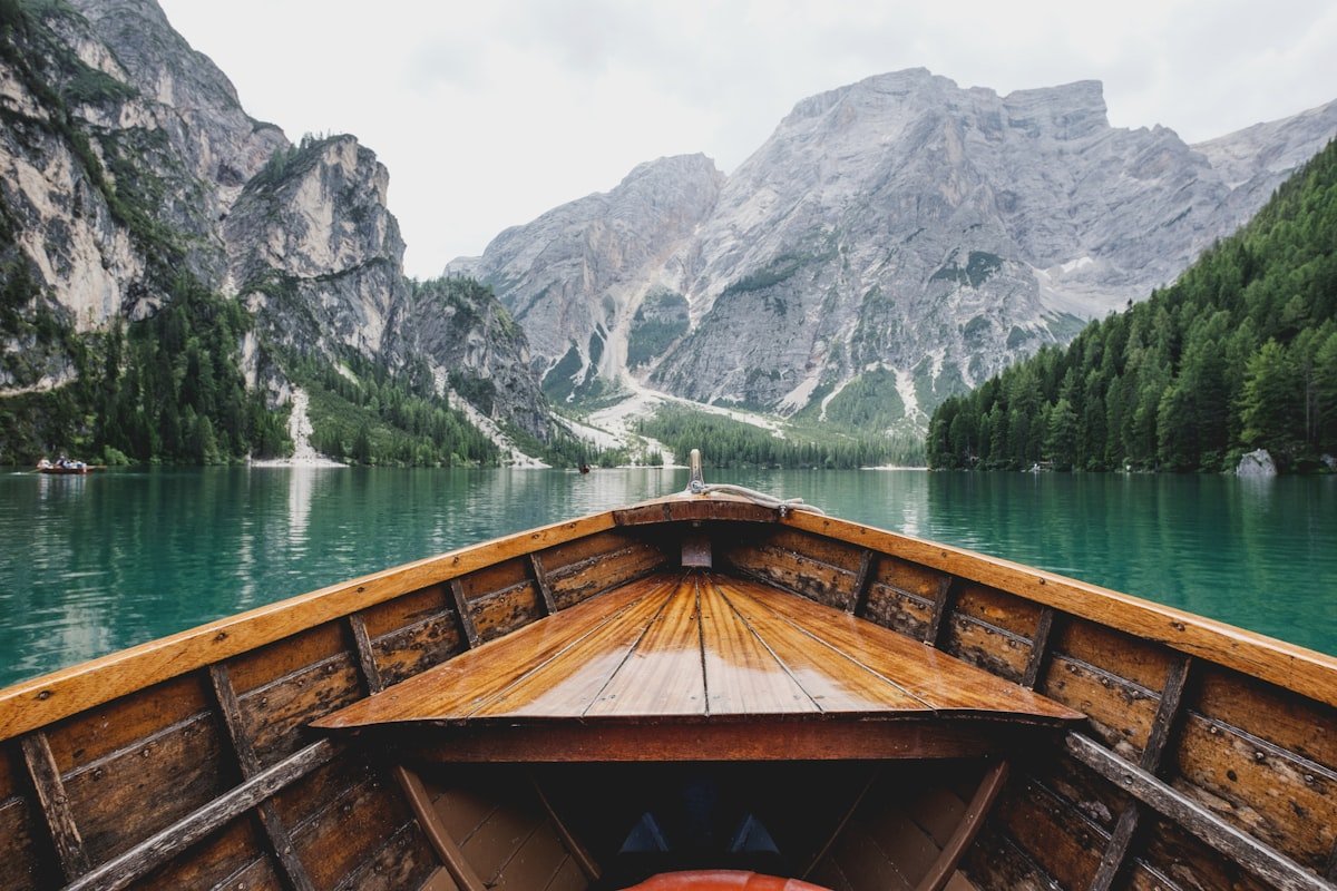 View from a wooden boat gliding across a turquoise alpine lake, off the beaten path