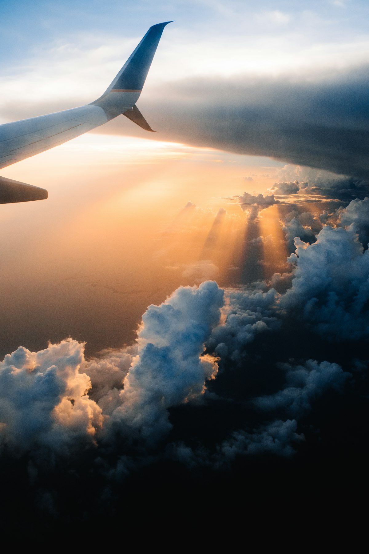 Airplane wing above a golden sea of clouds at sunset, symbolising life's journey