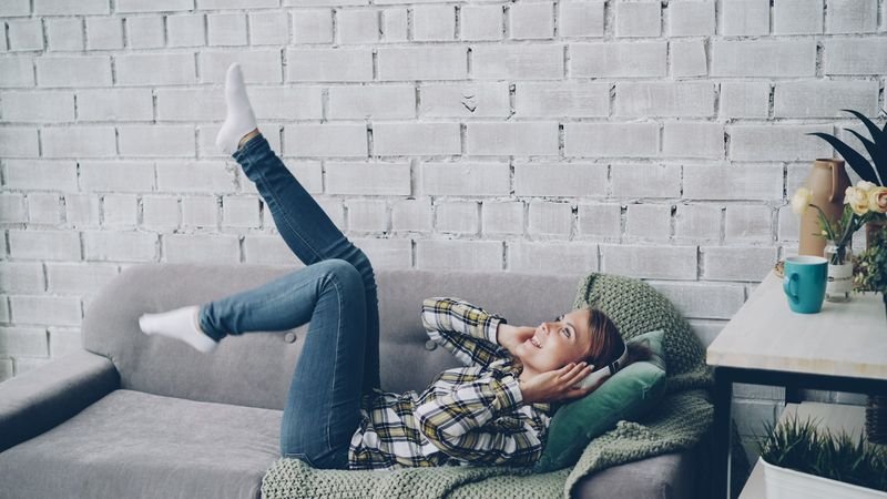 Woman lying on a sofa to explain lie vs lay, two confusing English verbs