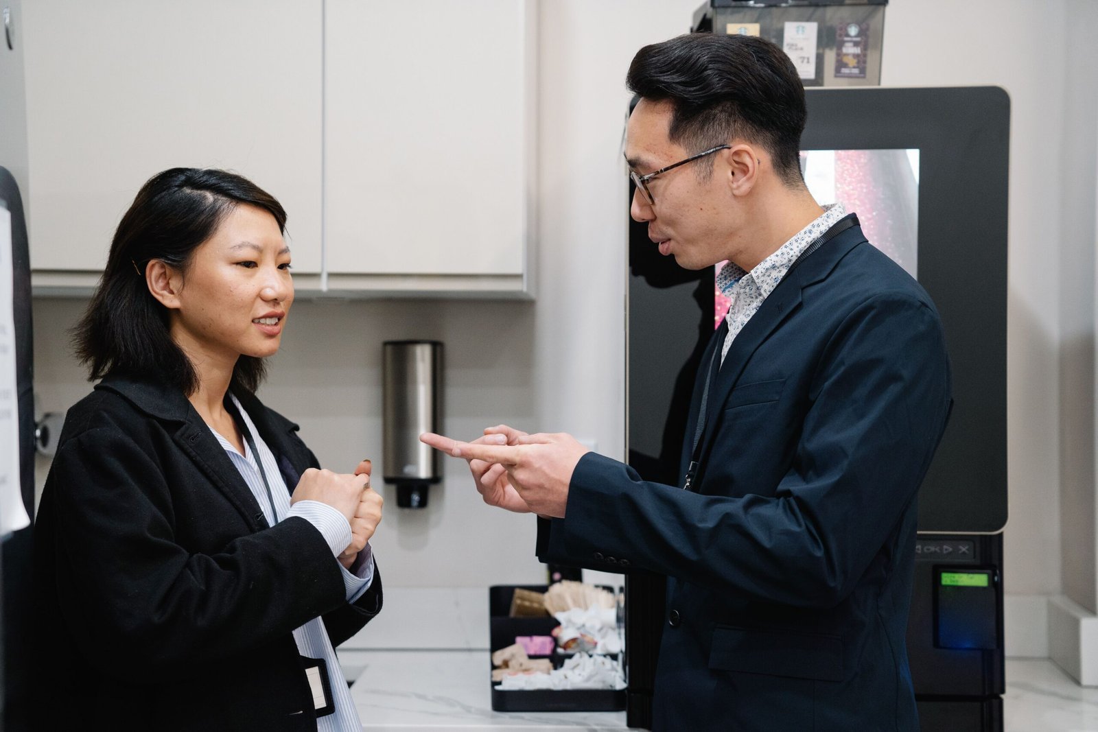 A man and a woman talking in the office kitchen