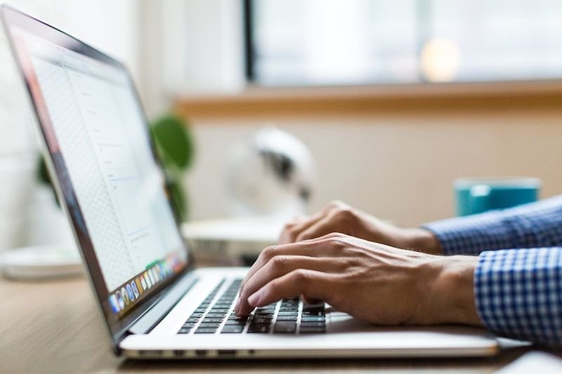 Professional typing a business email in English on a laptop