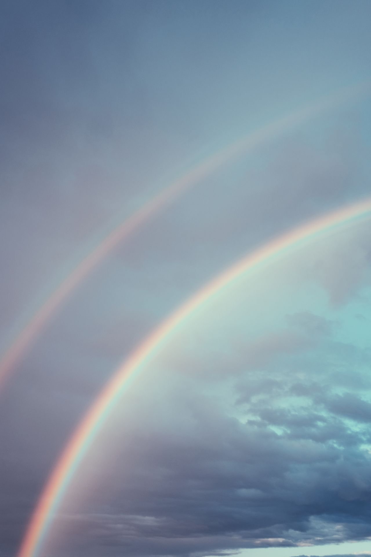 A double rainbow arcing across a dramatic evening sky