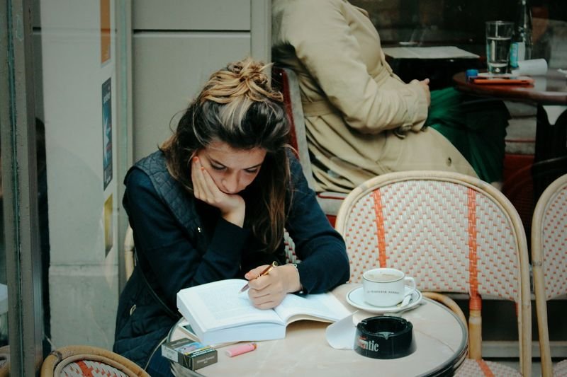 Woman studying English with a book and pen at a weekend cafe