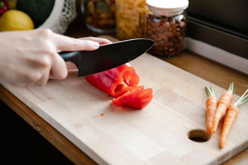 Person cutting vegetables in a kitchen, illustrating cut up and cut into phrasal verbs