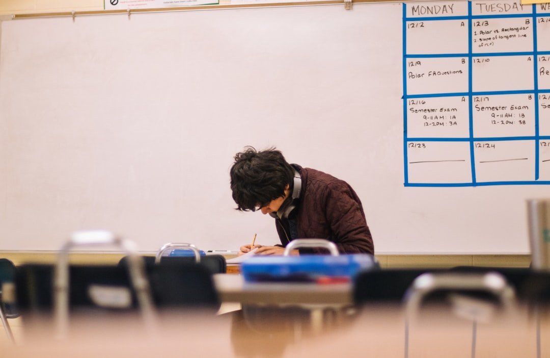 A student writing on paper at a desk in a classroom