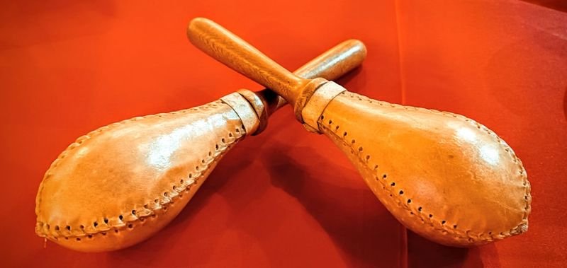 Two maracas — traditional Latin American percussion instruments — displayed on a vivid red background