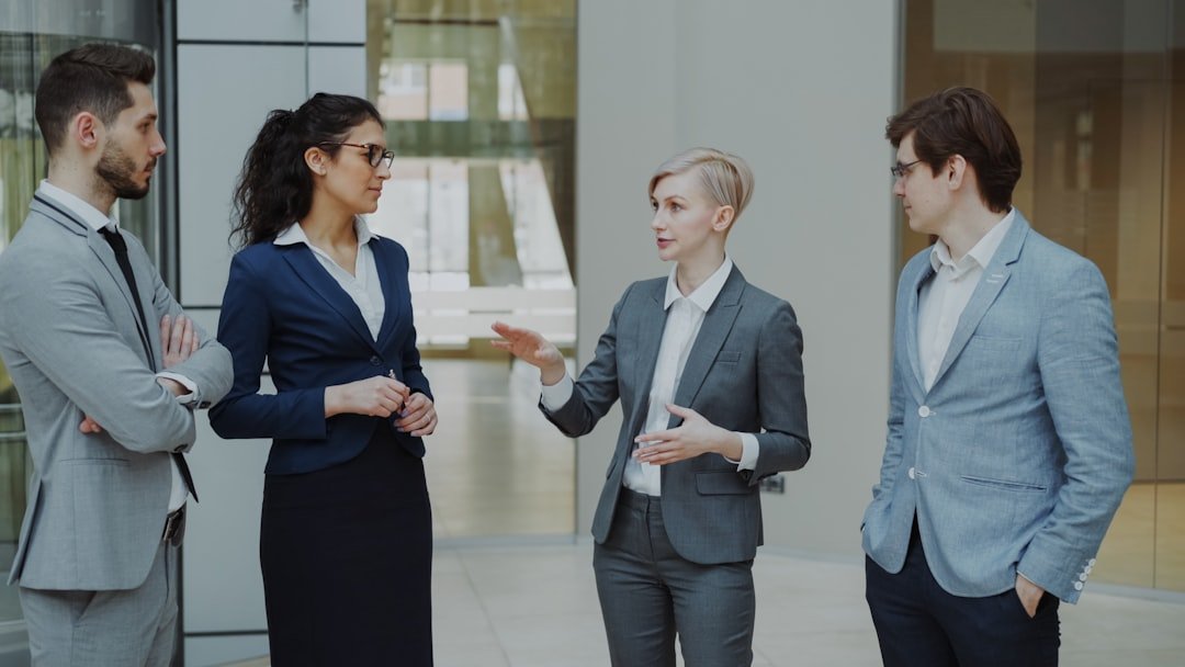 Businesswoman talking to her colleagues while standing in office lobby indoors. Group of business people discussing future de