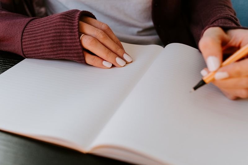 take down phrasal verb - person writing notes at desk