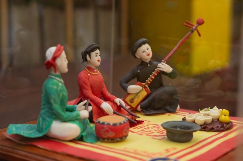 Traditional musicians in ceremonial dress playing string instruments from Southeast Asian culture