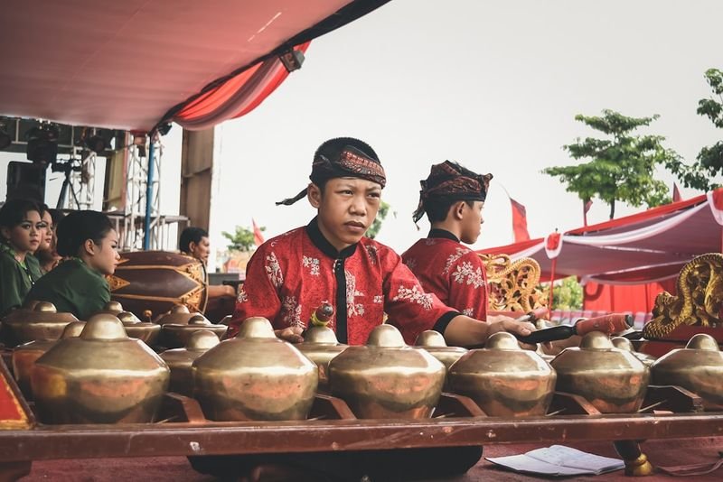 A woman in traditional red and white ceremonial dress performing at a cultural music event