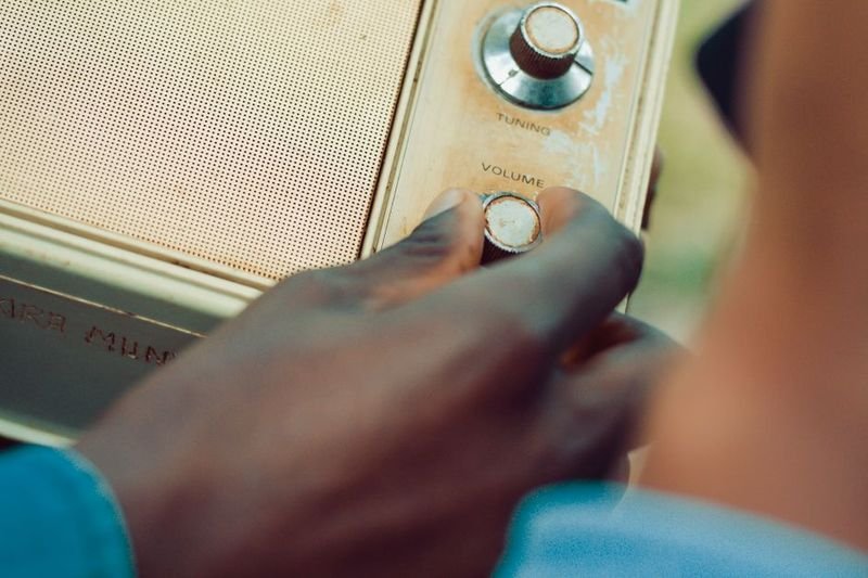 Hand adjusting volume knob on a radio — turn up and turn down phrasal verbs (turn up turn down 片語)